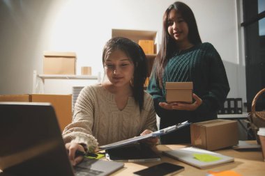 Başlangıçta küçük işletme KOBİ 'si, akıllı telefon veya tablet kullanan girişimci Afrikalı kadın paket ürün kutusu hazırlamak için çevrimiçi alışveriş siparişini alır ve kontrol eder.