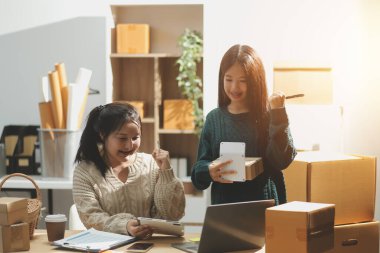 Başlangıçta küçük işletme KOBİ 'si, akıllı telefon veya tablet kullanan girişimci Afrikalı kadın paket ürün kutusu hazırlamak için çevrimiçi alışveriş siparişini alır ve kontrol eder.