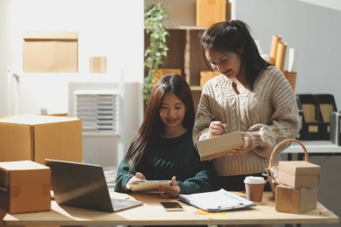 Başlangıçta küçük işletme KOBİ 'si, akıllı telefon veya tablet kullanan girişimci Afrikalı kadın paket ürün kutusu hazırlamak için çevrimiçi alışveriş siparişini alır ve kontrol eder.