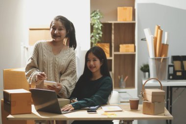 Başlangıçta küçük işletme KOBİ 'si, akıllı telefon veya tablet kullanan girişimci Afrikalı kadın paket ürün kutusu hazırlamak için çevrimiçi alışveriş siparişini alır ve kontrol eder.