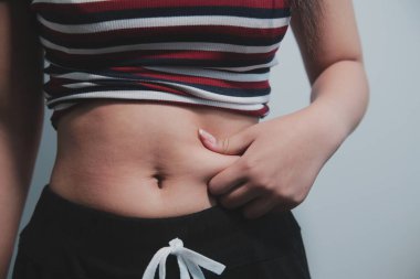 Kadın göbeği. Şişman kadın göbek yağlarını tutuyor. diyet yaşam tarzı konsepti karın kaslarını zayıflatmak ve sağlıklı mide kaslarını şekillendirmek için.