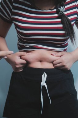 Kadın göbeği. Şişman kadın göbek yağlarını tutuyor. diyet yaşam tarzı konsepti karın kaslarını zayıflatmak ve sağlıklı mide kaslarını şekillendirmek için.