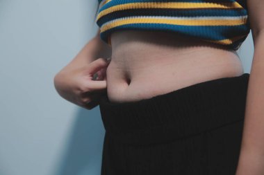 Kadın göbeği. Şişman kadın göbek yağlarını tutuyor. diyet yaşam tarzı konsepti karın kaslarını zayıflatmak ve sağlıklı mide kaslarını şekillendirmek için.