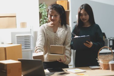 Başlangıçta küçük işletme KOBİ 'si, akıllı telefon veya tablet kullanan girişimci Afrikalı kadın paket ürün kutusu hazırlamak için çevrimiçi alışveriş siparişini alır ve kontrol eder.