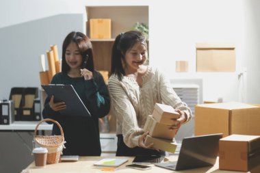 Başlangıçta küçük işletme KOBİ 'si, akıllı telefon veya tablet kullanan girişimci Afrikalı kadın paket ürün kutusu hazırlamak için çevrimiçi alışveriş siparişini alır ve kontrol eder.