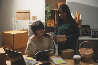 Başlangıçta küçük işletme KOBİ 'si, akıllı telefon veya tablet kullanan girişimci Afrikalı kadın paket ürün kutusu hazırlamak için çevrimiçi alışveriş siparişini alır ve kontrol eder.