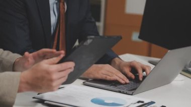 Genç iş adamı ofiste dizüstü bilgisayarla çalışıyor.