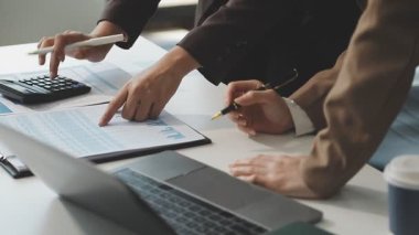 İş ekibi birlikte çalışır ve hesap makinesi ve dizüstü bilgisayardaki finansal verileri analiz eder.