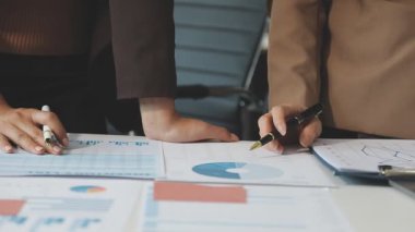 İş kadını elinde bir hesap makinesi tutuyor ve bir dizüstü bilgisayardaki grafiği analiz ediyor.