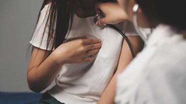 Kadın doktor steteskopla hastayı kontrol ediyor.
