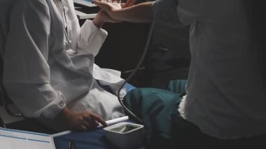 Hastane koğuşunda steteskoplu bir hastayı muayene eden doktor.