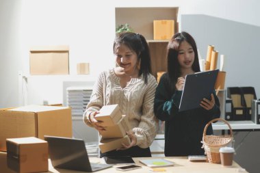 Başlangıçta küçük işletme KOBİ 'si, akıllı telefon veya tablet kullanan girişimci Afrikalı kadın paket ürün kutusu hazırlamak için çevrimiçi alışveriş siparişini alır ve kontrol eder.