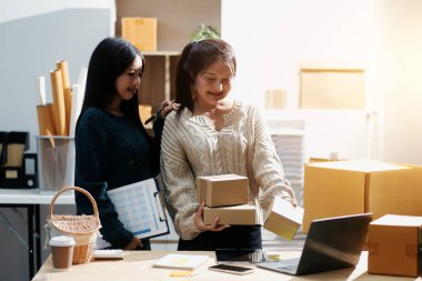 Başlangıçta küçük işletme KOBİ 'si, akıllı telefon veya tablet kullanan girişimci Afrikalı kadın paket ürün kutusu hazırlamak için çevrimiçi alışveriş siparişini alır ve kontrol eder.