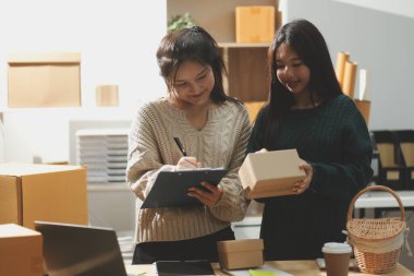 Başlangıçta küçük işletme KOBİ 'si, akıllı telefon veya tablet kullanan girişimci Afrikalı kadın paket ürün kutusu hazırlamak için çevrimiçi alışveriş siparişini alır ve kontrol eder.