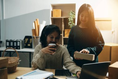 Başlangıçta küçük işletme KOBİ 'si, akıllı telefon veya tablet kullanan girişimci Afrikalı kadın paket ürün kutusu hazırlamak için çevrimiçi alışveriş siparişini alır ve kontrol eder.