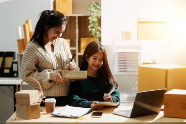 Başlangıçta küçük işletme KOBİ 'si, akıllı telefon veya tablet kullanan girişimci Afrikalı kadın paket ürün kutusu hazırlamak için çevrimiçi alışveriş siparişini alır ve kontrol eder.