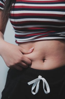 Kadın göbeği. Şişman kadın göbek yağlarını tutuyor. diyet yaşam tarzı konsepti karın kaslarını zayıflatmak ve sağlıklı mide kaslarını şekillendirmek için.