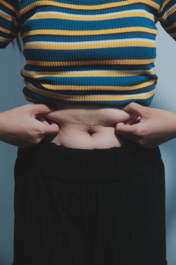 Kadın göbeği. Şişman kadın göbek yağlarını tutuyor. diyet yaşam tarzı konsepti karın kaslarını zayıflatmak ve sağlıklı mide kaslarını şekillendirmek için.