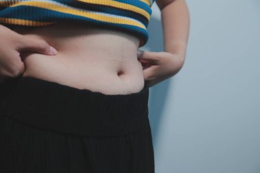 Kadın göbeği. Şişman kadın göbek yağlarını tutuyor. diyet yaşam tarzı konsepti karın kaslarını zayıflatmak ve sağlıklı mide kaslarını şekillendirmek için.