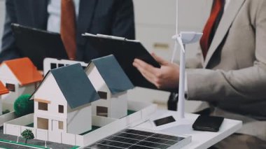 Minyatür insanlar: iş adamı ve ev modeli masada. Gayrimenkul işi ve sigorta kavramı.