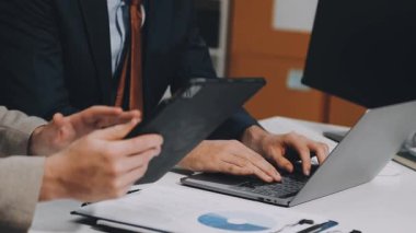 Ofiste dizüstü bilgisayarı ve belgeleri olan takım elbiseli bir işadamı. Dizüstü bilgisayarı ve tableti olan iş adamı