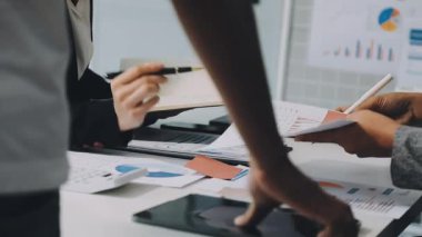 Genç Asyalı iş adamları ofiste çalışıyor. İş adamları ofiste bir rapor tartışıp planlıyorlar.