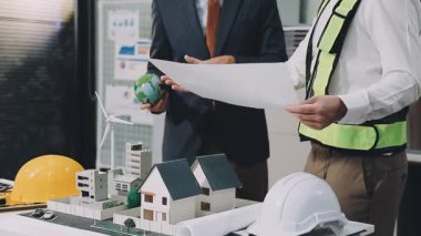 İnşaat mühendisi ofis inşaatının planıyla birlikte proje üzerinde çalışıyor.