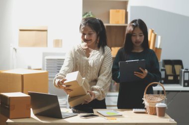 Başlangıçta küçük işletme KOBİ 'si, akıllı telefon veya tablet kullanan girişimci Afrikalı kadın paket ürün kutusu hazırlamak için çevrimiçi alışveriş siparişini alır ve kontrol eder.