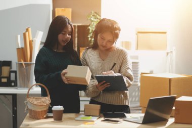 Başlangıçta küçük işletme KOBİ 'si, akıllı telefon veya tablet kullanan girişimci Afrikalı kadın paket ürün kutusu hazırlamak için çevrimiçi alışveriş siparişini alır ve kontrol eder.