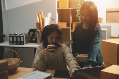 Başlangıçta küçük işletme KOBİ 'si, akıllı telefon veya tablet kullanan girişimci Afrikalı kadın paket ürün kutusu hazırlamak için çevrimiçi alışveriş siparişini alır ve kontrol eder.