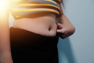 Kadın göbeği. Şişman kadın göbek yağlarını tutuyor. diyet yaşam tarzı konsepti karın kaslarını zayıflatmak ve sağlıklı mide kaslarını şekillendirmek için.