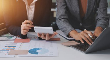 Muhasebe şirketi kazançlı nakit akışı için finansman ve vergilendirme planlaması, ofiste çalışan denetçi ve muhasebeci ekibi, mali verileri ve muhasebe kayıtlarını hesap makinesiyle analiz eder.