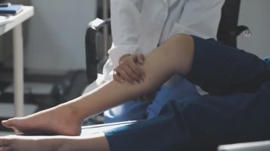 Doktor, klinikteki kadın hastanın bacağını muayene ediyor.