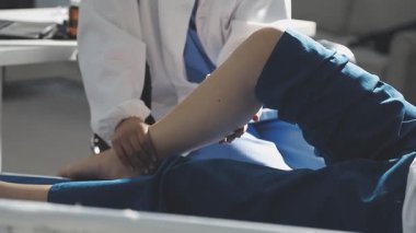 Hastane koğuşundaki kanepede oturan beyaz üniformalı genç kadın doktor..