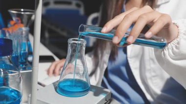 Mavi üniformalı bilim adamı elinde sıvı test tüpü tutuyor.