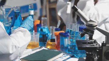 Yakın plan - mikroskop ve tüplerle laboratuvardaki bilim adamlarının elleri