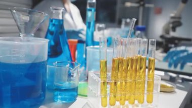 Arka planda mavi sıvı bulunan kimya laboratuvarı.