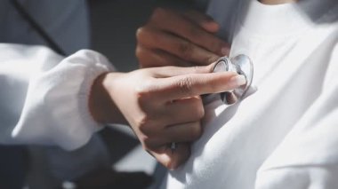 Doktor ellerinin steteskop tutması ve klinikteki hastaları kontrol etmesi.