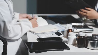 Tıp doktoru beyaz önlüklü ve siyah üniformalı. Elinde tablet var.