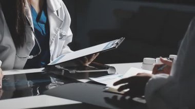 Doktor hastanın röntgenini tutuyor ve tabletine bakıyor.