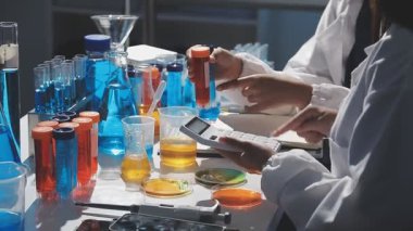 Laboratuvar asistanı test tüpleri ve mataralarla çalışıyor.