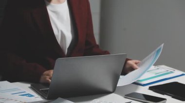 Modern ofis odasında dizüstü bilgisayar ve mali belge kullanan iş kadını, borsa raporu