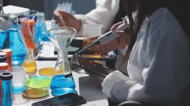 Laboratuvarda kimya laboratuarı sıvısı ve kimyasal ekipmanlarla dolu şişeyi tutan bilim adamının yakın çekimi.