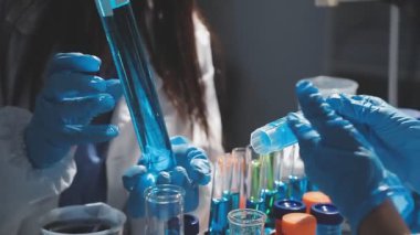 Koruyucu eldivenlerdeki bilim adamı laboratuarda sıvı içeren tüpü tutuyor.