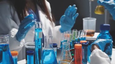 Laboratuvar çalışanı koruyucu eldivenleriyle laboratuarda matarayı tutuyor..