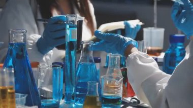 yakın plan - koruyucu gözlüklü laboratuvar asistanı test tüpü ve matara tutuyor