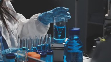 Laboratuvarda bir şişe sıvı tutan bilim adamı..