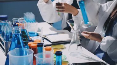Genç bilim kadını elinde sıvı ve kimyasal sıvı şişesi tutuyor..