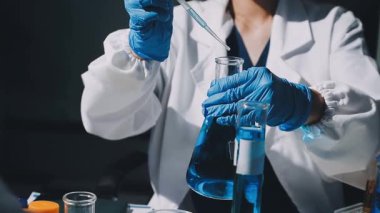 Laboratuvarda deney tüpleriyle çalışan bir bilim adamı. Bilim, kimya, teknoloji ve tıp konsepti.