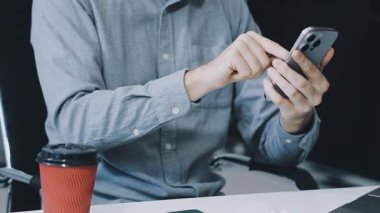 Smartphone kullanarak ve dizüstü bilgisayarda yazarak adam